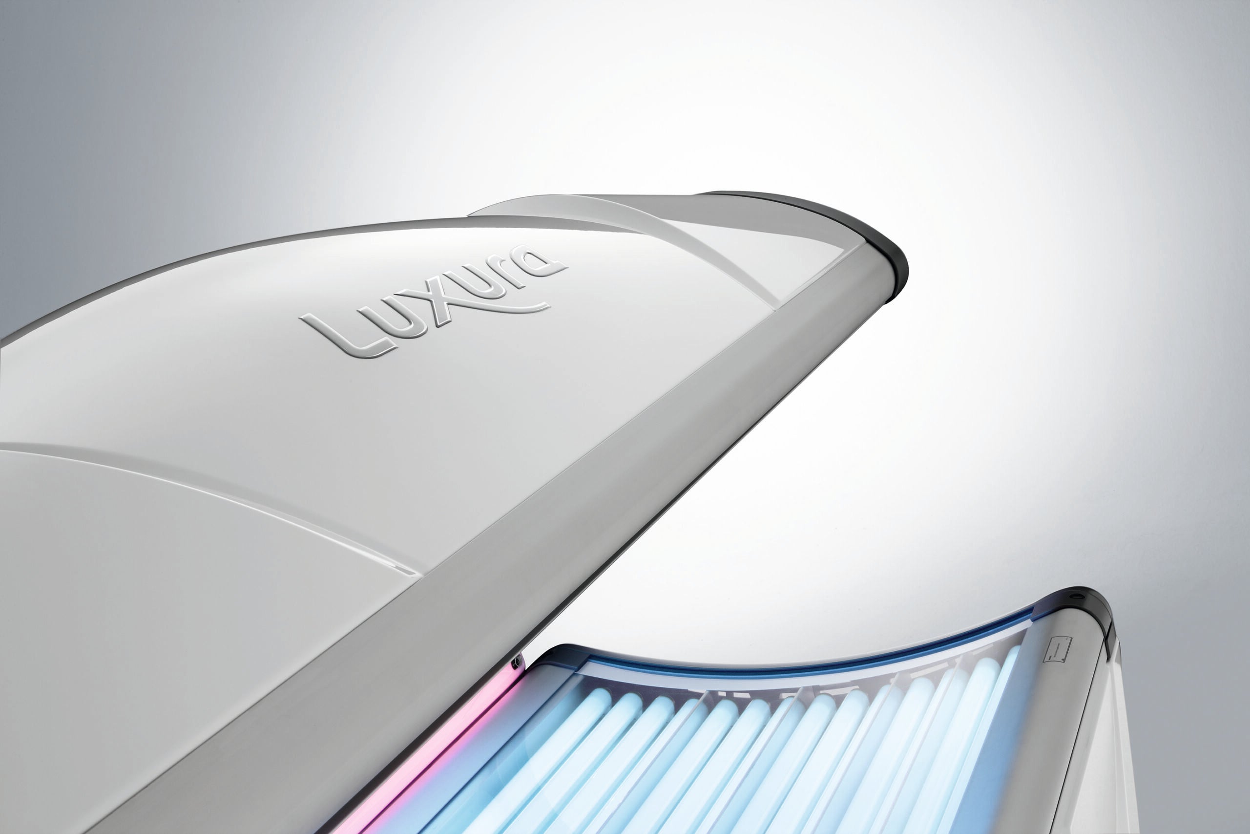 Close-up of the Luxura X3 canopy showing the embossed Luxura logo and illuminated blue lamps beneath the curved top.