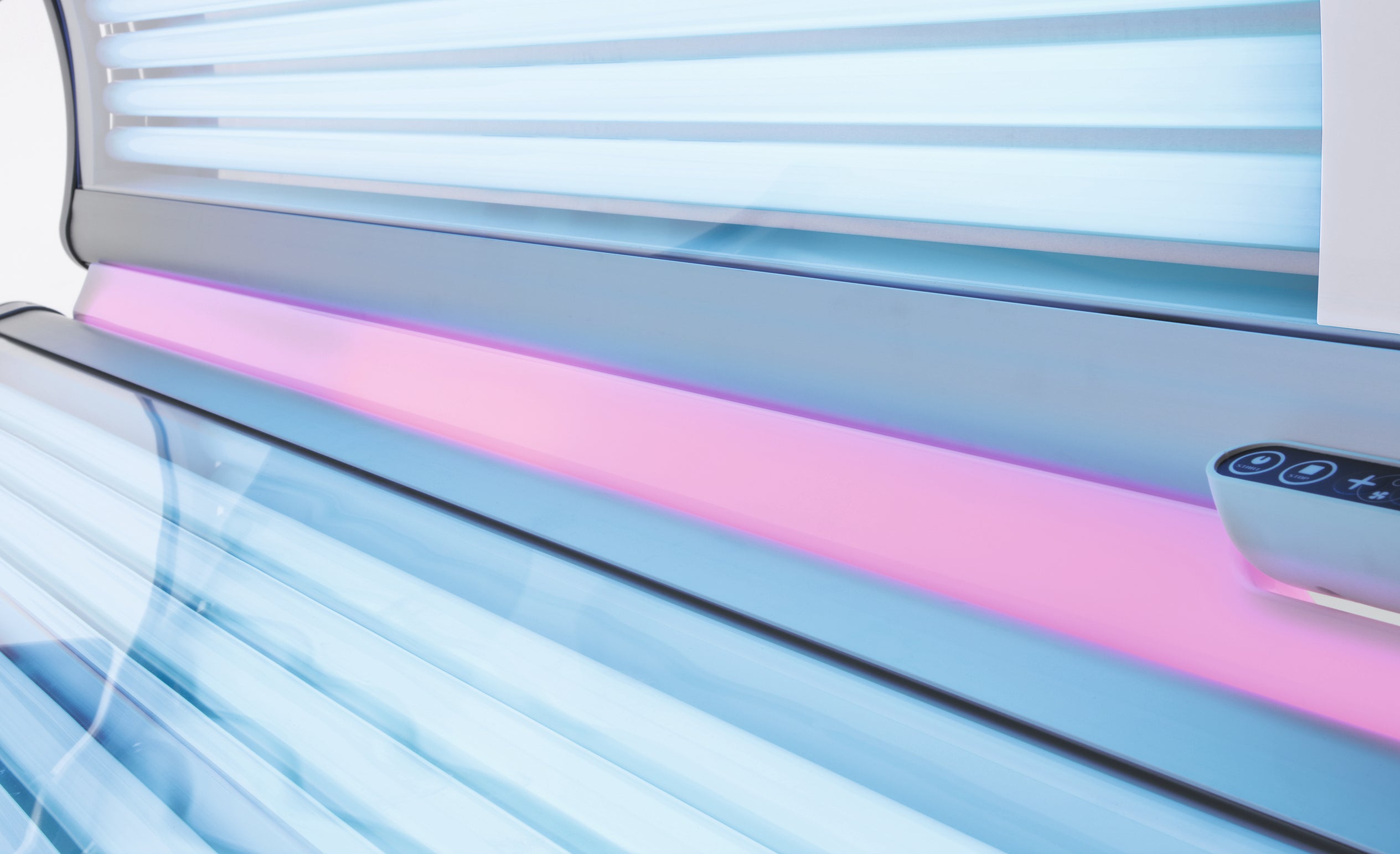 Luxura X3 tanning bed shown open with blue tanning tubes and a decorative pink light strip across the bench.