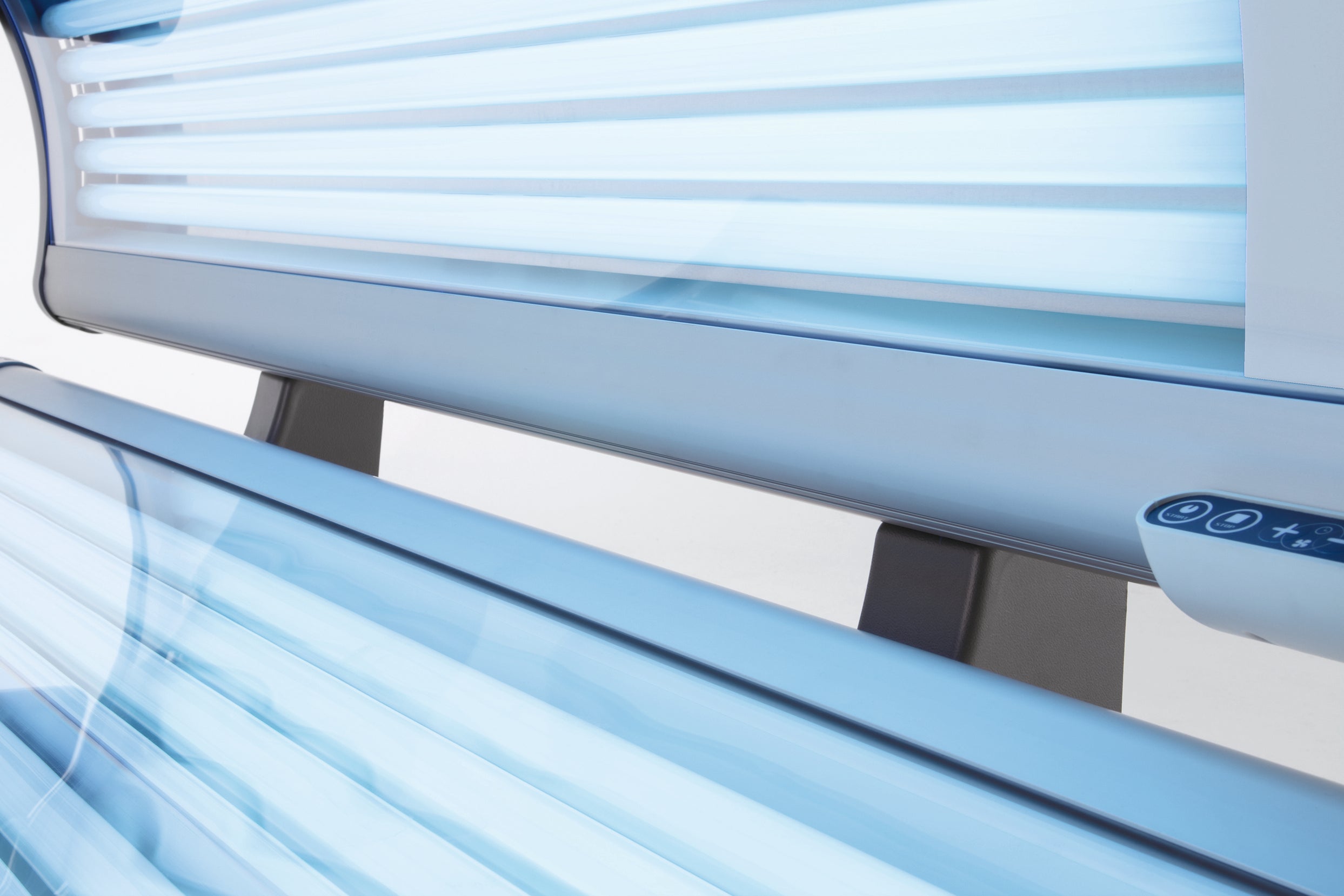 Close-up view of the Luxura X3 tanning bed interior showing bright blue tanning tubes on the canopy and bench.