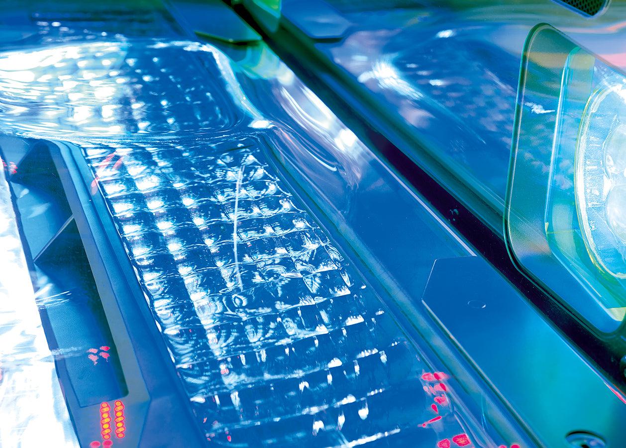 Close-up of the Luxura Vegaz 9200 contoured bench and crystal cooling panel illuminated with bright blue and turquoise lighting.