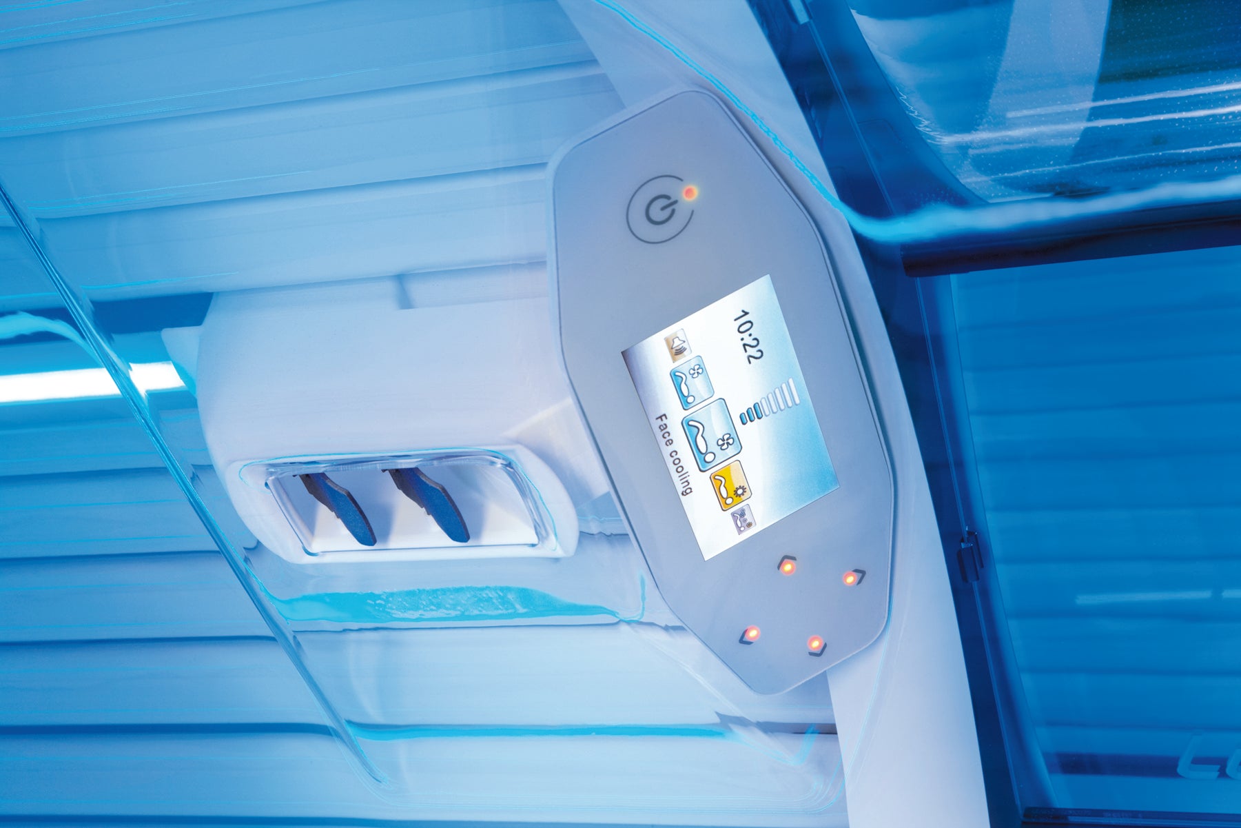 Close-up view inside the Luxura X7 sunbed showing the central digital control panel surrounded by curved blue tanning lamps.
